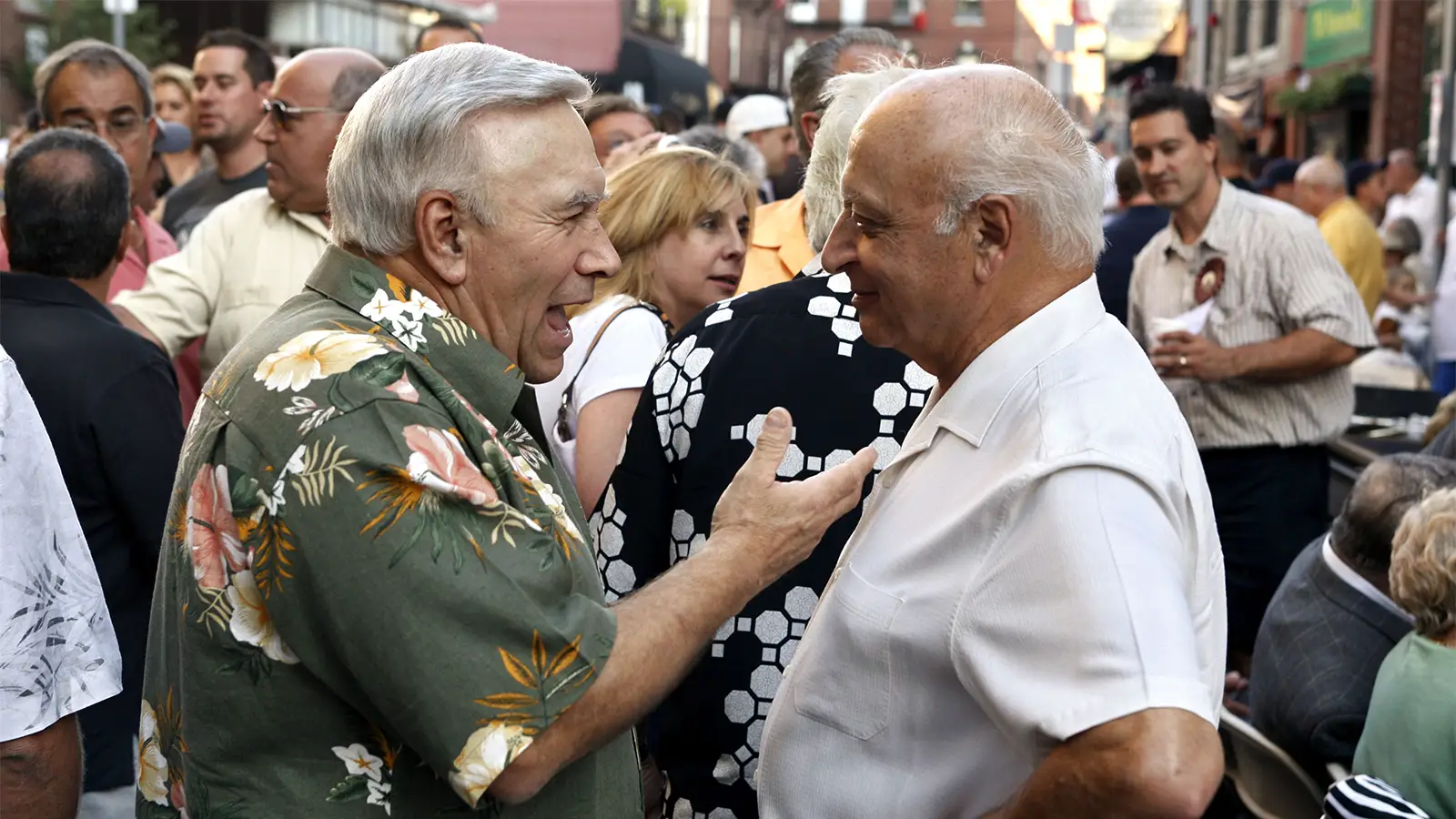 A photo of two senior men talking during a block party.