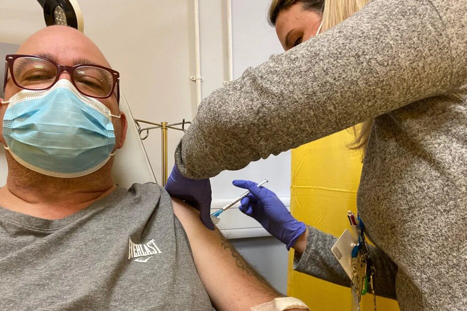 A photo of a female physician vaccinating a mature man.