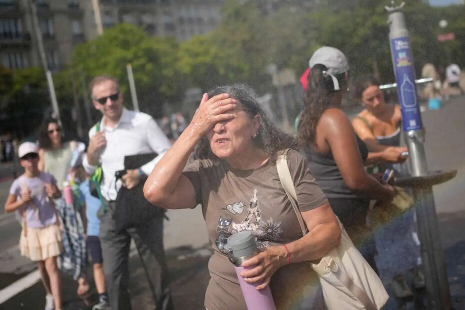 Tourists cooling off at a public water fountain in Paris (AP Photo/Christophe Ena, File)