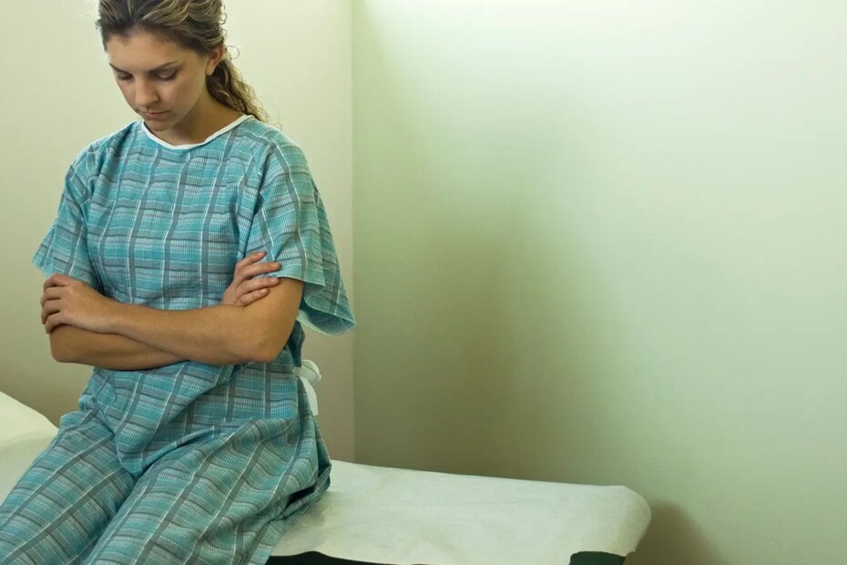 A photo of a woman sitting on an examination table.