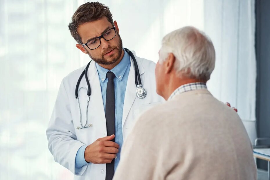 A photo of a male physician listening to his senior male patient.