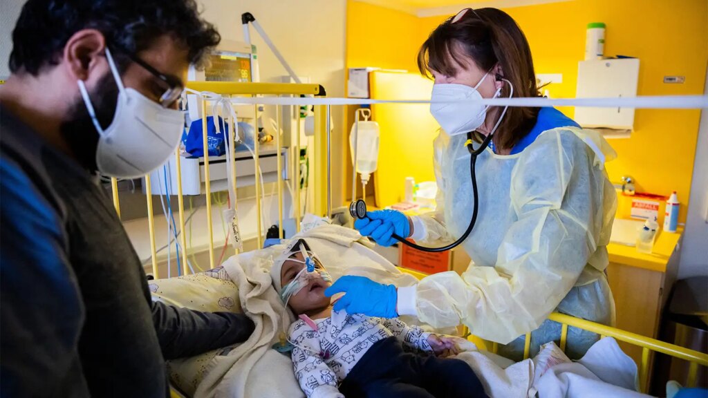 Kids’ Risk of Severe Respiratory Infection Rises With Comorbidity Count A photo of a female physician at the bedside of a child hospitalized for a respiratory tract infection.