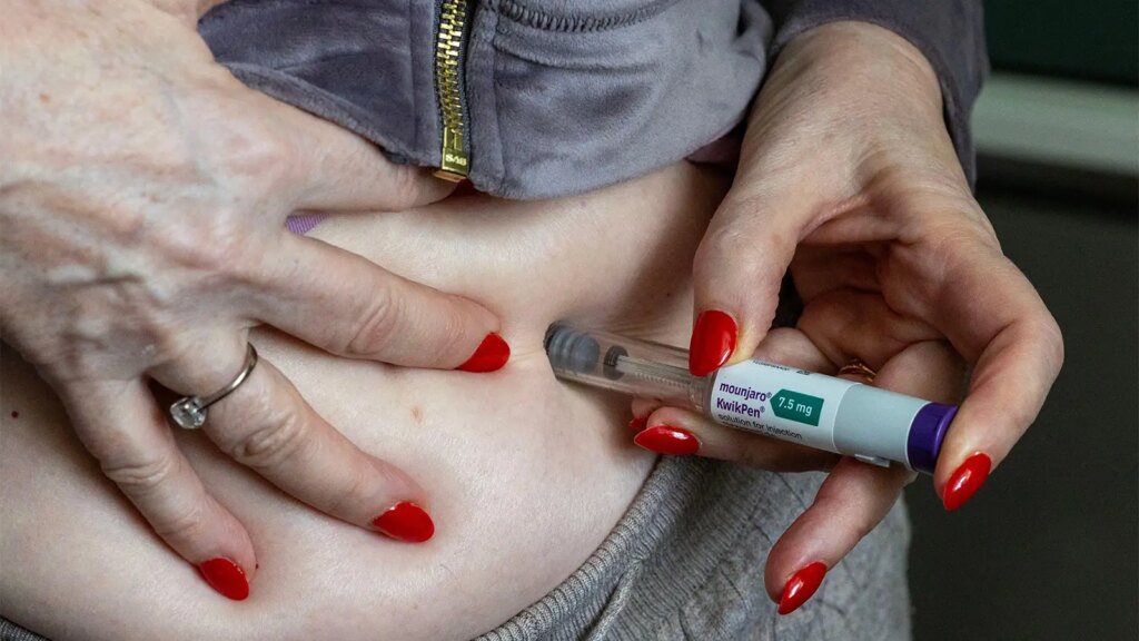 Large Study Links GLP-1s to Lower Risk of Multiple Cancers A photo of a woman self injecting her abdomen with a Mounjaro KwikPen.