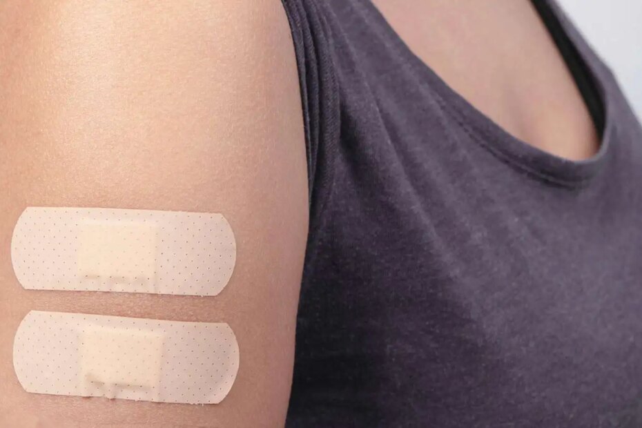 A woman’s arm with two vaccine bandaids.
