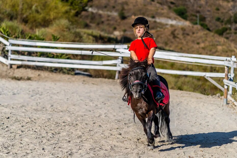 A photo of a girl with Achondroplasia riding a pony.