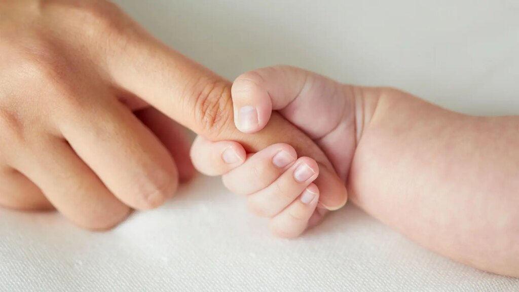 A photo of an infant grasping his mother’s finger.
