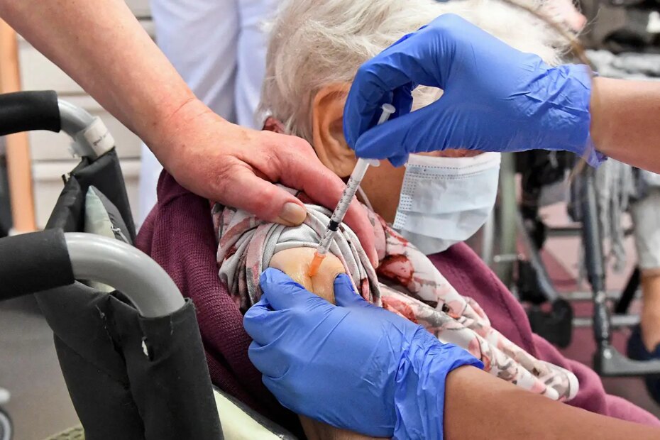 A photo of a senior woman receiving a vaccination in a nursing home.
