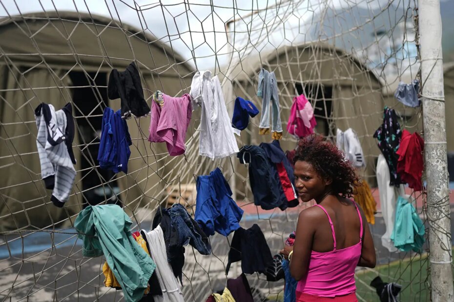 A photo of Nataly Mayora hanging clothes on a soccer goal net at a center for displaced people in La Guaira, Venezuela.