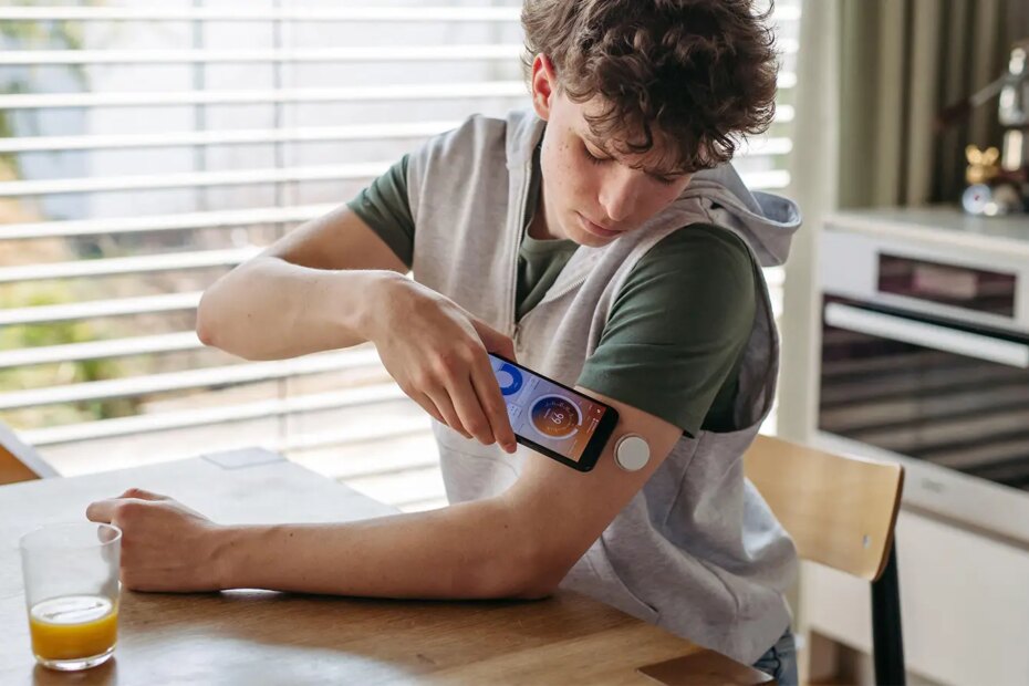 A photo of a teen male checking his continuous glucose meter with his smartphone.