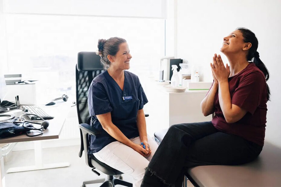 A photo of a female physician and her smiling female patient in an examination room.