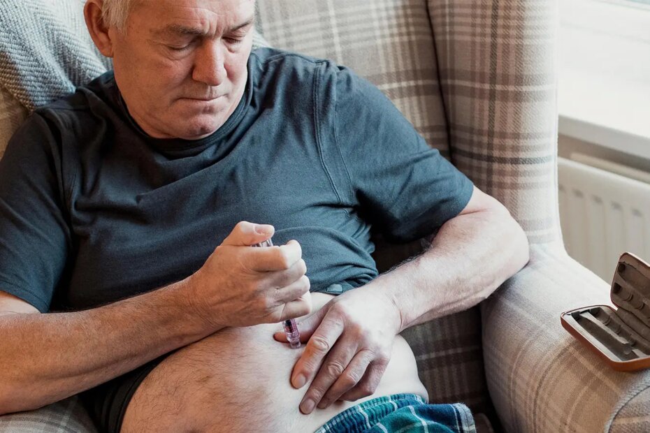 A photo of a senior man at home injecting insulin into his belly fat.