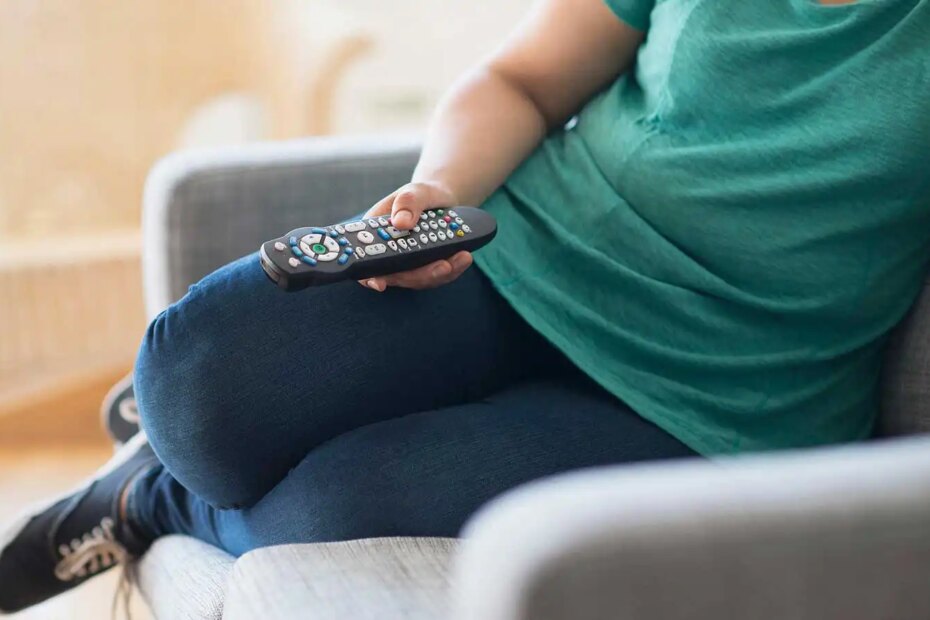 Woman sitting on sofa with a remote control.