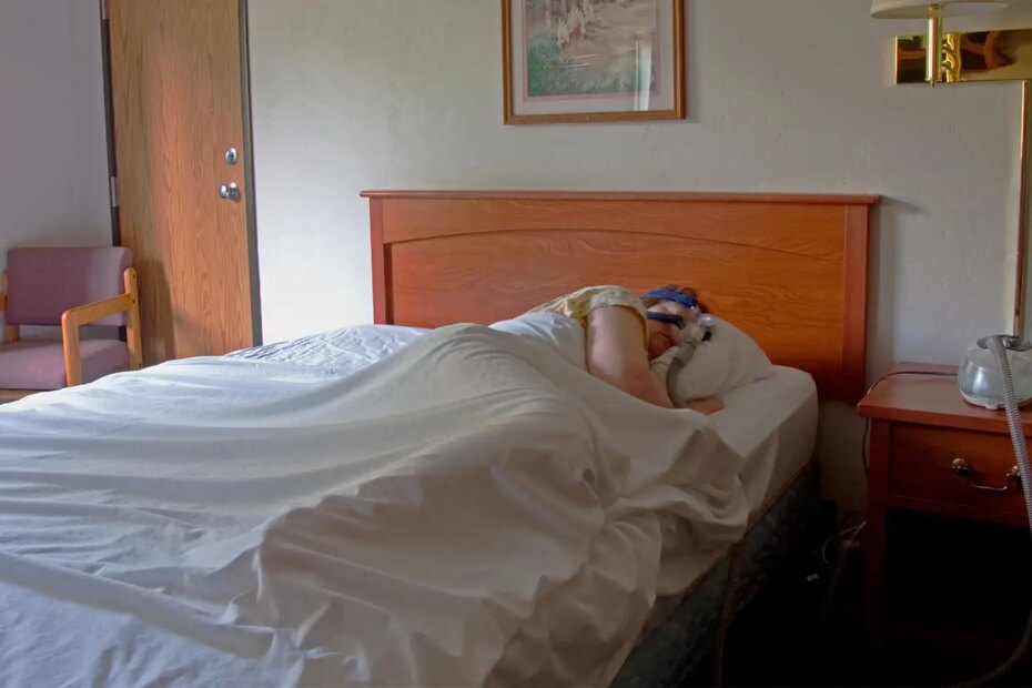 A photo of a woman sleeping while wearing a sleep apnea mask.