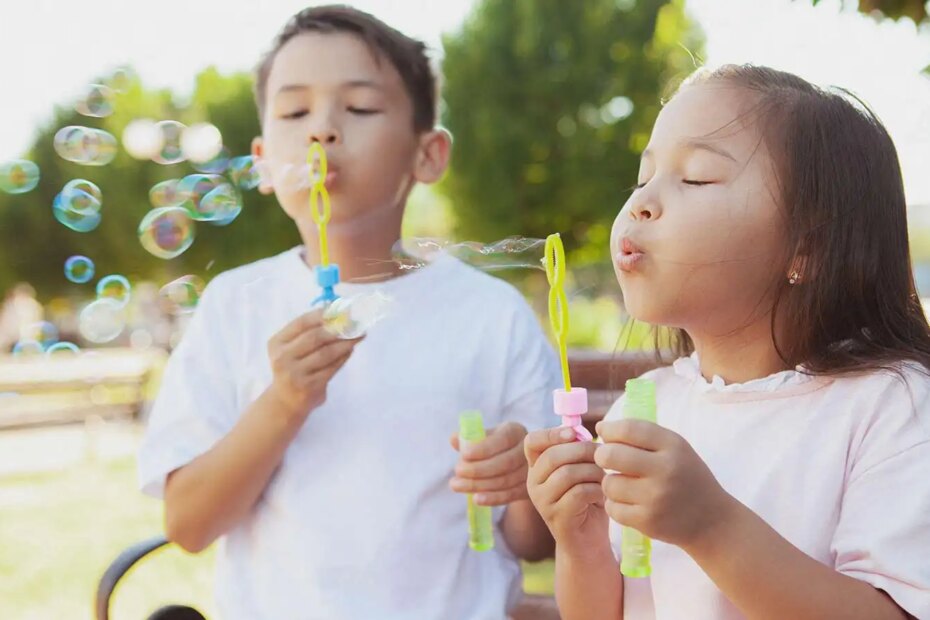 Happy little kids blowing bubbles outdoors in the park.