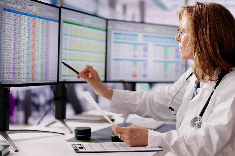 A photo of a female physician at a desk consulting CPT codes in a spreadsheet.