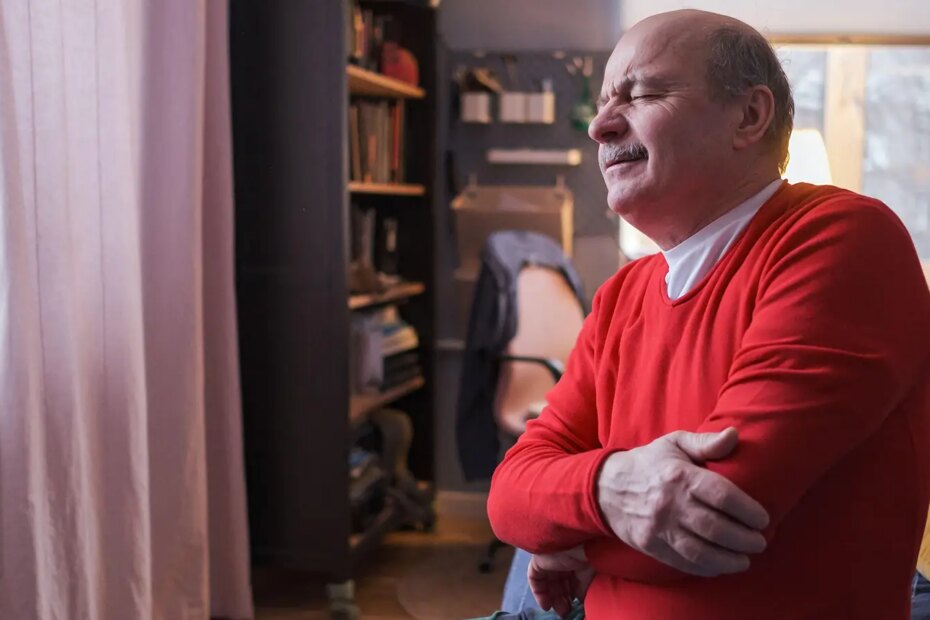 A photo of a senior man wincing from elbow arthritis pain.