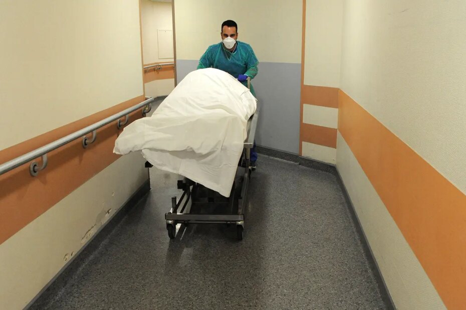 A photo of a healthcare worker pushing a gurney to the hospital morgue.