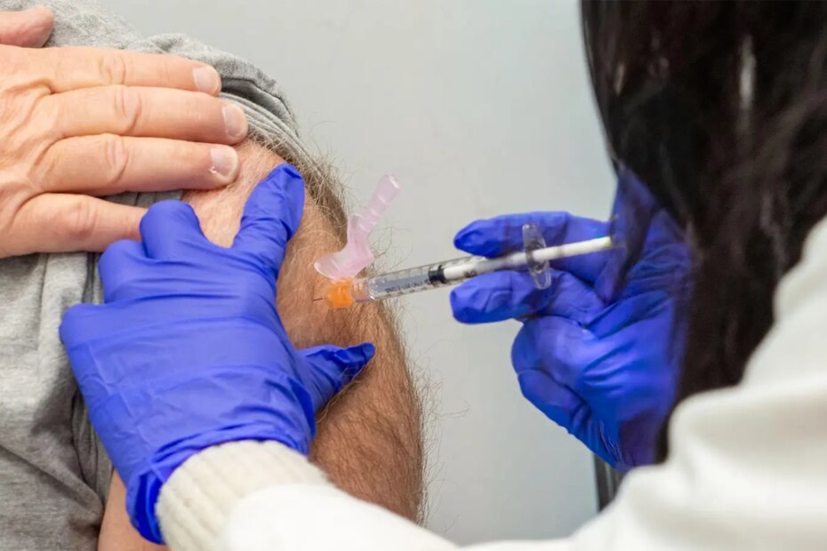 A photo of a female healthcare worker vaccinating a mature man.