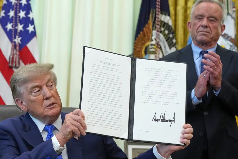 A photo of Trump holding a signed executive order about vaccines as Robert F. Kennedy Jr. looks on.