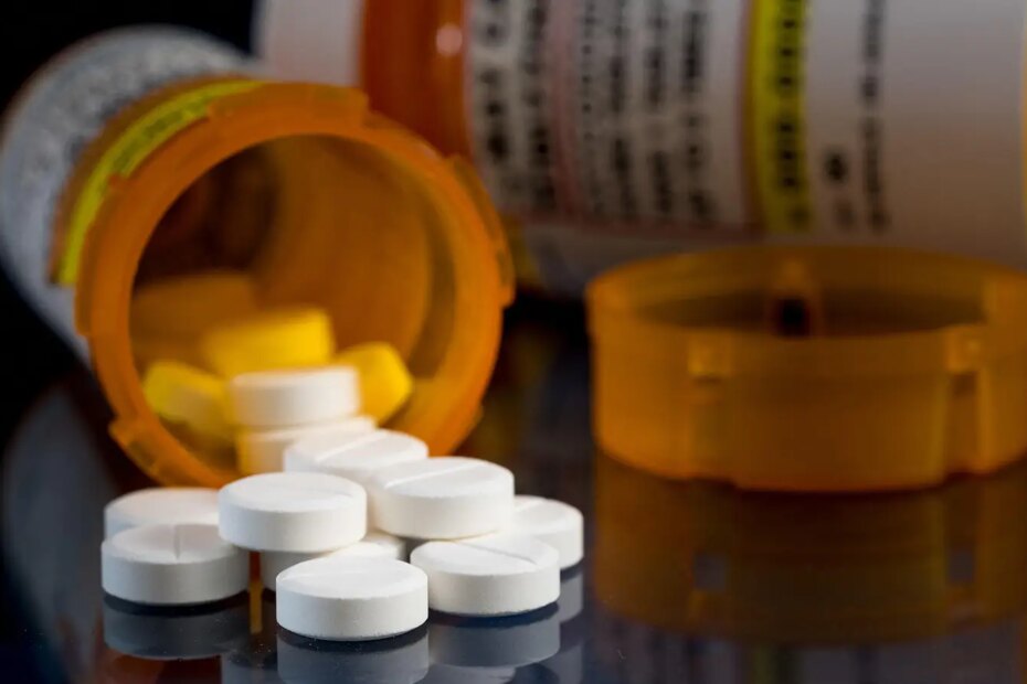 A photo of white pills spilled from a prescription medication bottle.