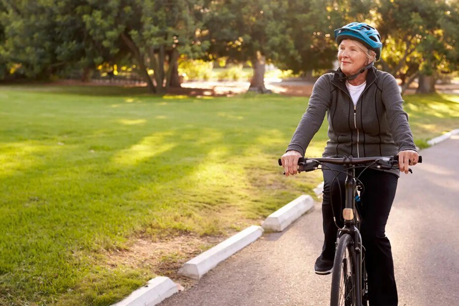 A photo of a senior woman riding her bicycle in a park.
