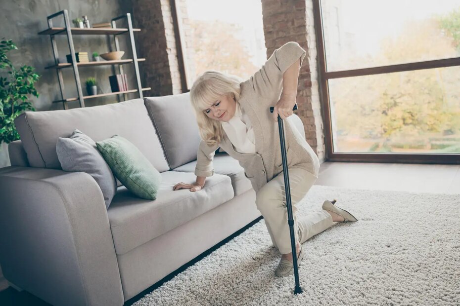 A photo of a senior woman struggling to stand up with a cane.