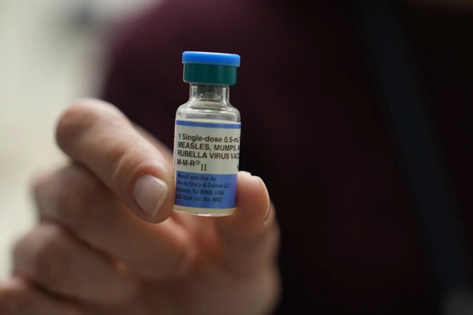 A photo of a man holding a vial of the MMR vaccine.