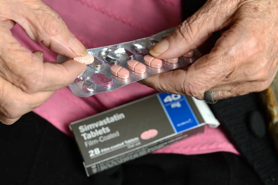 A photo of a senior woman holding a statin pill and blisterpack.